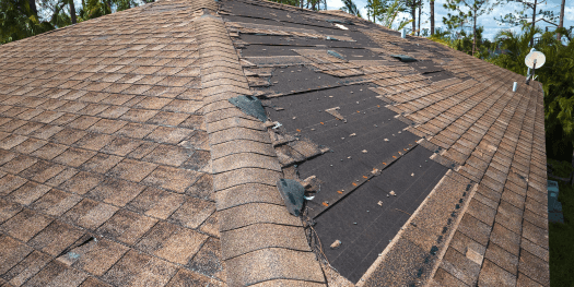 house roof with missing shingles due to wind damage